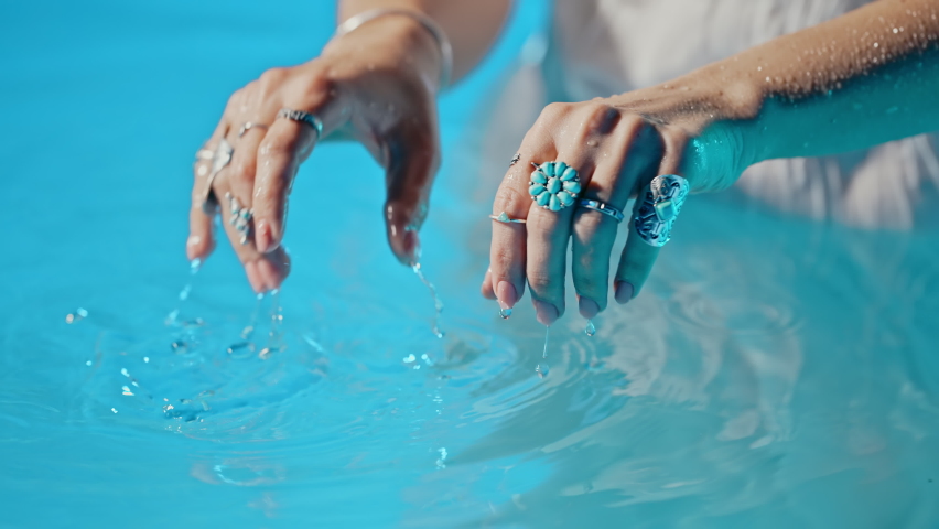 Woman in water imitates playing music on piano. Boho jewelry, rings with stones on fingers. Girl in white dress swimming in pool or lake. Femininity, trend, hippie style concept. Royalty-Free Stock Footage #1093813381