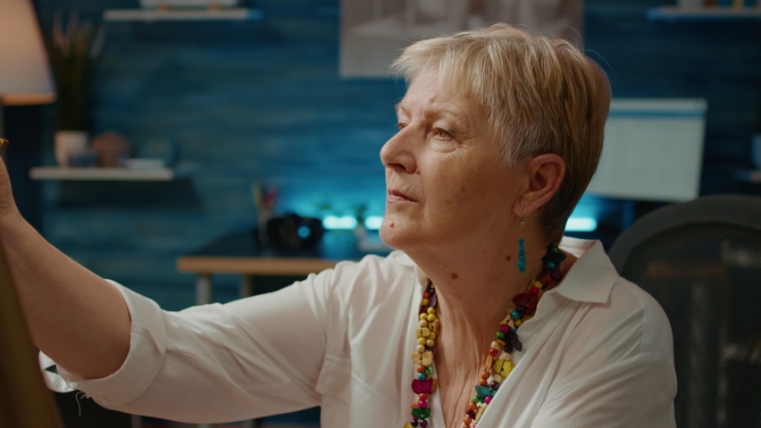 Senior woman using artistic hobby and tools to create artwork design at home, creative skills. Drawing authentic vase model on canvas to do masterpiece on board, art imagination.