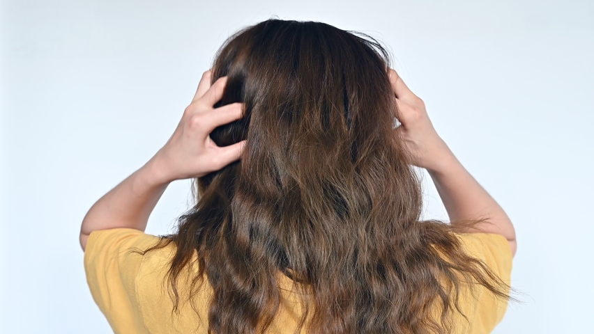 Rear view of Asian woman scratching her scalp caused of itchy scalp. Dandruff and an inflammatory skin condition called seborrheic dermatitis are the most common causes of itchy scalp. | Shutterstock HD Video #1093816781