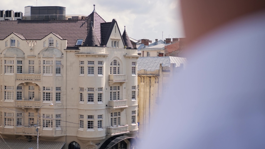 Closeup man stands in the balcony with great views of old city enjoying beautiful morning feeling happy, deep breathing thinking. Businessman standing in luxury hotel during business trip or