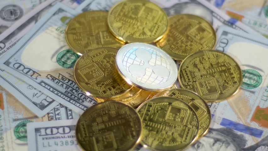 Cryptocurrency Ripple XRP altcoin real coins lying on dollar bills, flashlight close up