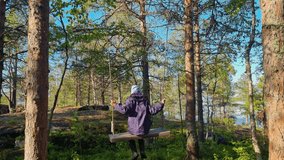 Girl swinging on swings in the forest. 4k video footage