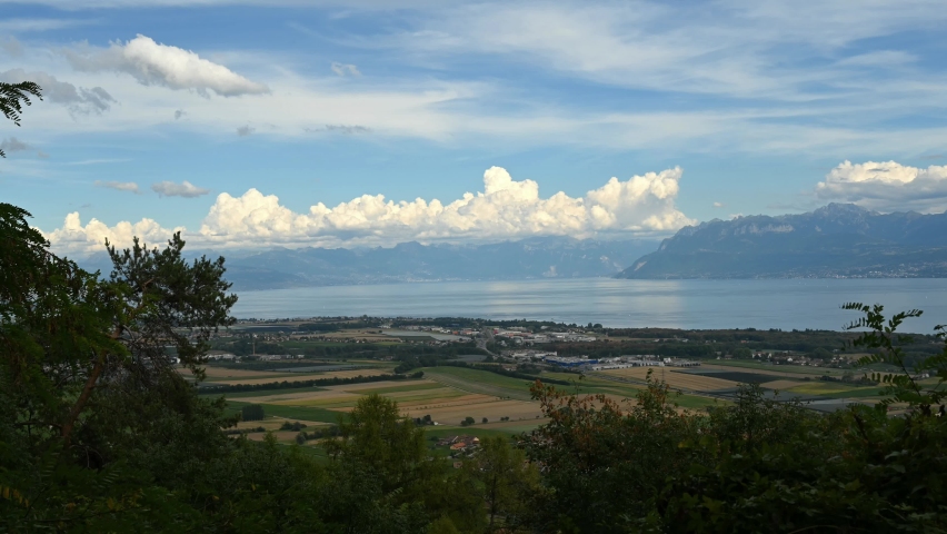 Landscape of lake, mountain and city. Time lapse of Aubonne, Vaud, Switzerland. High angle view towards Lake Geneva and city in sunny day in summer.