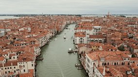 Panoramic drone footage of a traditional Italian city on the water, with the Grand Canal among orange-roofed houses. Venice, Italy, video on a sunny day