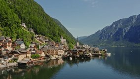Non-white village with traditional houses, located on the shore of a picturesque lake, in a lowland between the Alps. Austria, Hallstatt, drone video