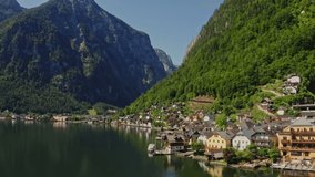 A small Austrian town located on the coast of a picturesque lake at the foot of green mountains. Austria, Hallstatt, drone video