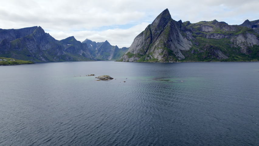 Aerial forwarding shot of scenic mountains in Reinefjorden on Lofoten Island with Stand up Paddler on a nice summer day