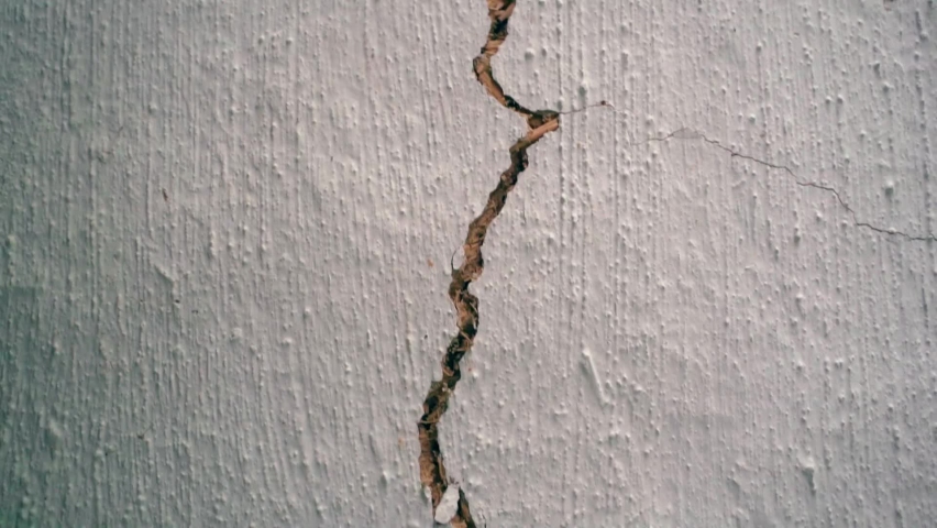 A crack in the white clay wall of an old house. Camera movement along the crack in the ceiling close-up. Loss of building integrity Royalty-Free Stock Footage #1093838425
