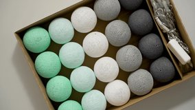 Cotton balls lights packed in cartoon box. Ready do setup. Creative decoration with colorful cotton light balls garland in home interior. Top view, flat lay - Powered by Shutterstock - Get 15% off with code: PIKWIZARD15