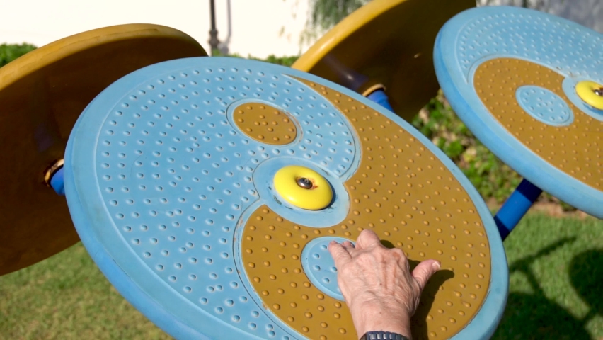 slow motion, senior woman exercising hands and arms on a fitness equipment outdoors.
