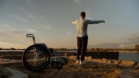young man in a wheelchair is now on his feet. A young man got rid of his disability.The man recovered from the disease.Against a beautiful sunset