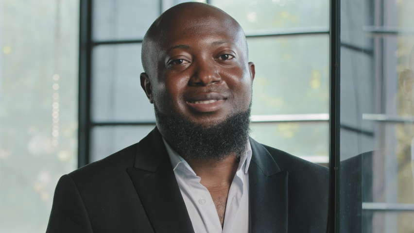 Positive african american businessman male team leader general manager banker lawyer handsome adult 40s bearded man wears black formal suit friendly looking at camera smiling posing in modern office | Shutterstock HD Video #1093848383