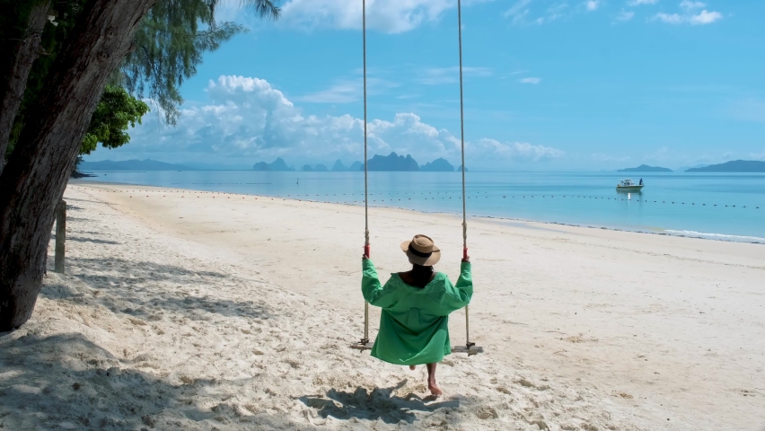 Woman on the beach of the tropical Island Naka Island near Phuket Thailand, and a woman on a swing on the beach in Thailand. 