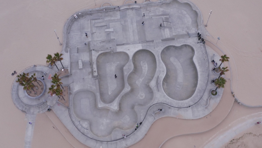Aerial view of people skating at the Venice beach skate park, in Los Angeles, USA - reverse, tilt, drone shot