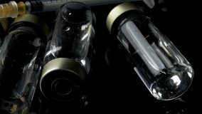 4k panning video of close up on vaccine vials and syringe on dark moody background concept for pandemic vaccination campaign, liquid medicine and disease treatment injection