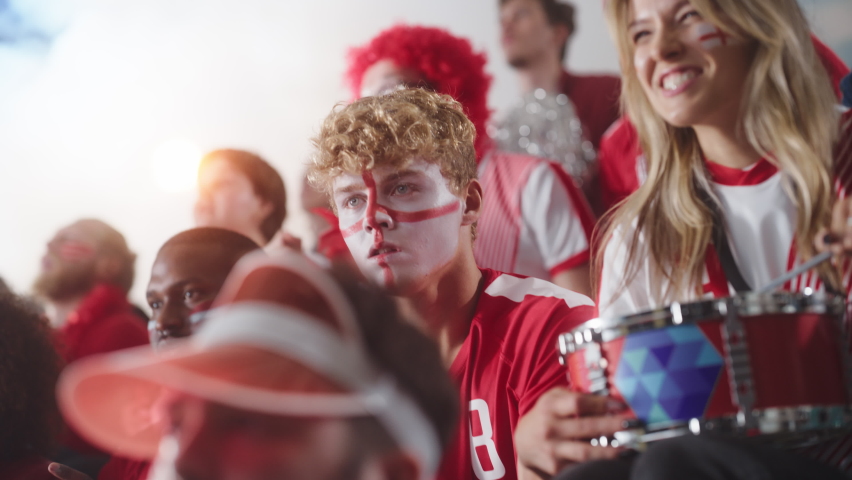 Sport Stadium Sport Event: Intense Caucasian Man Cheering, Whistling. Crowd of Fans with Painted Faces Stand up, Cheer, Shout for Red Soccer Team to Win, Celebrate Scoring Goal, Championship Victory