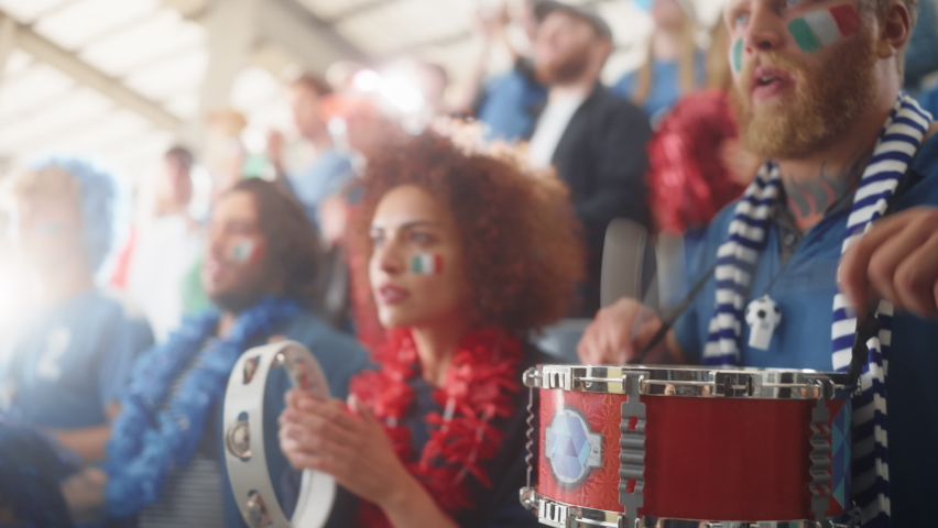 Sport Stadium Soccer Match: Portrait of Beautiful Bi Racial Fan Girl with Italian Flag Painted Face Cheering Team to Win, Beating Tambourine. Crowd Celebrate Goal, Championship Victory. Slow Motion