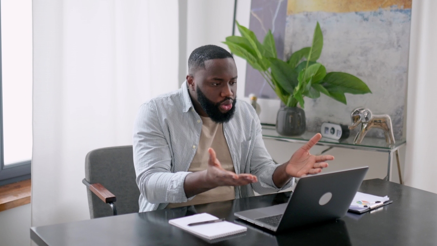 Confused angry annoyed african american business man, company ceo, sit at desk in modern office, have irritation conversation with colleagues, shows financial graphs, yelling, upset by bad report | Shutterstock HD Video #1093868091