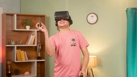 Young man with VR or virtual reality gogles playing video game with joystick on metaverse at home - conept of technology, relaxation and entertainment.