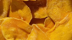 Dried mango slices close-up on a white. Top view. Closeup. Mango chips background. Dehydrated crispy fruit slices, pieces. Heap of sun-dried yellow fruit. Healthy meal. Top view, flat lay. 4K Footage.