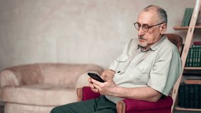 Confident grandfather chatting smartphone browsing internet sitting in vintage armchair at home. Pensive aged 70s man playing online video games scrolling social networks reading news message doctor 