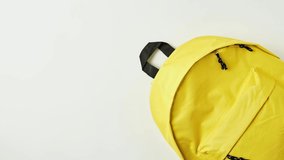 stop motion of a yellow backpack with assorted school supplies of various colors getting inside it on a white background - Powered by Shutterstock - Get 15% off with code: PIKWIZARD15