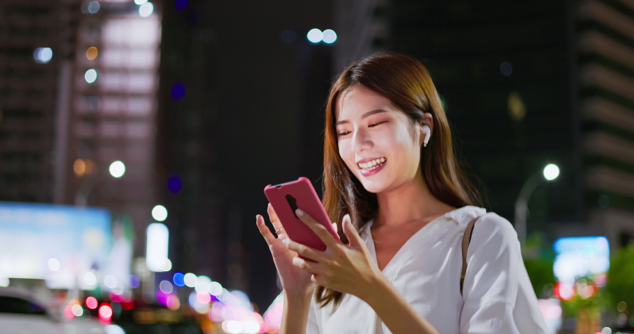 asian woman speak to phone by wearing wireless earbuds while walking on the city street at night Royalty-Free Stock Footage #1093888951