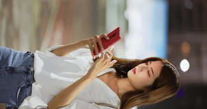 vertical of asian businesswoman feel eye tired and neck pain while using smartphone on the blurred street background in the evening