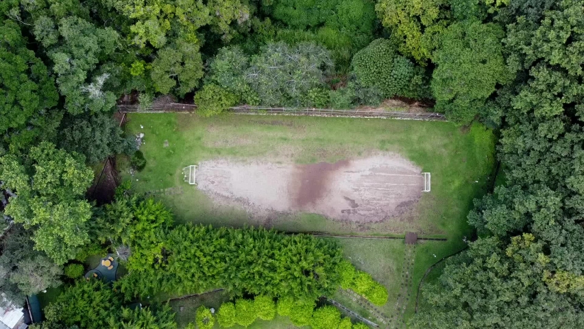 aerial shot of a dirt soccer field in the middle of the forest