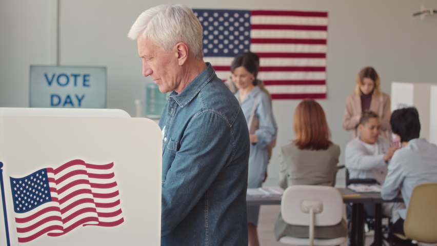 Medium slowmo of diverse men and women with ballots coming to vote booth to go through procedure of voting on Elections Day Royalty-Free Stock Footage #1093901987