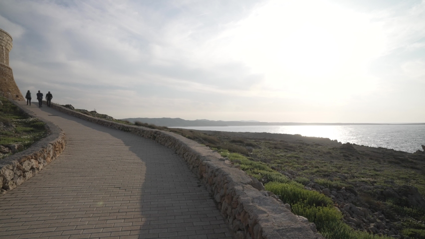 People walking up pathway to Fornells Tower fortress at sunset, Fornells, Menorca, Balearic Islands, Spain, Mediterranean, Europe
