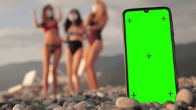 Phone with a green screen and tracking dots on the beach, three multi-racial girls in swimsuits dancing in the background. Chromakey - Powered by Shutterstock - Get 15% off with code: PIKWIZARD15