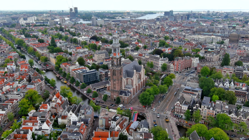Beautiful aerial Amsterdam view from above, Netherlands ft. drone view of Westerkerk church and narrow canal with bridge, street, boats, architectures and traffic around city downtown in Holland Royalty-Free Stock Footage #1093907809