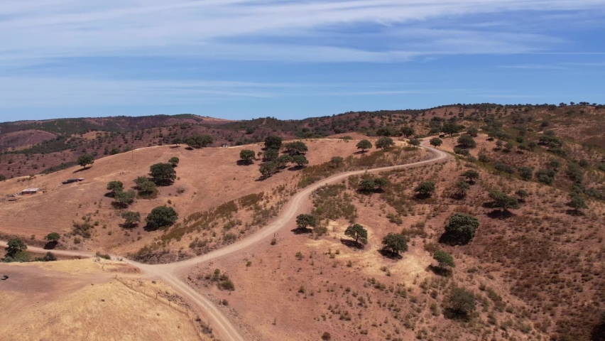 A Vista Of Winding Dirt Road On Sloping Hills And Mountains In Alentejo, Portugal. Aerial Drone Shot