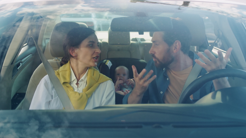 Footage of beautiful young Caucasian couple having argument, gesturing in morning. Family fight. Littlie baby boy sitting in baby car seat in background. Trip, child care, protection, safe Royalty-Free Stock Footage #1093928795