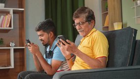 side view of father and son separately using mobile phone on sofa at home - concept of Mobile phone addiction, modern lifestyle, and family bonding.