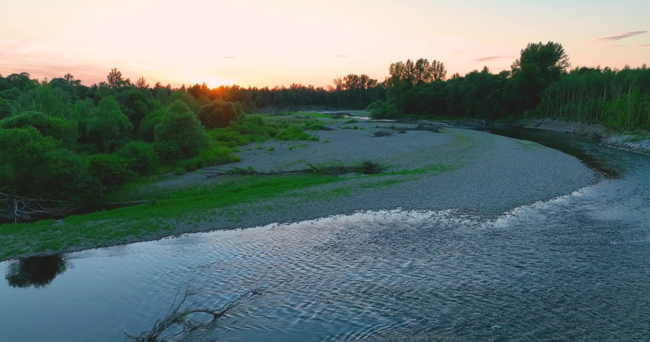 Beautiful sunset over the rocky river, mountain river. A rocky river in the middle of a forest in 4K. Aerial view of tranquil river reflecting sky, amid lush green landscape, aerial view