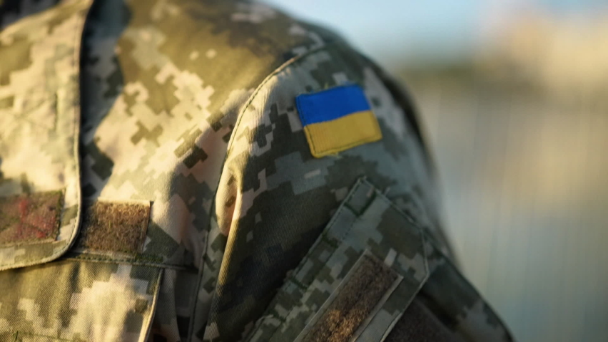Soldier of the Ukrainian army. Chevron yellow-blue flag close-up. Shoulder of a man in military uniform, pixel. Defender of Ukraine. Slow motion. Royalty-Free Stock Footage #1093941817