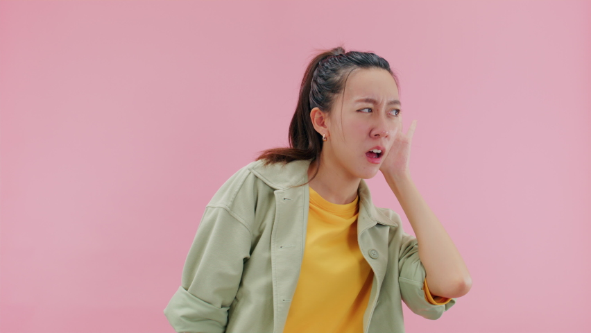 PRICK UP EAR, Focused attractive young asian woman having hearing problems sufferings from noise keeping hand near ear to listen clearer showing I can't hear you gesture.Isolated on Pink Background | Shutterstock HD Video #1093943789