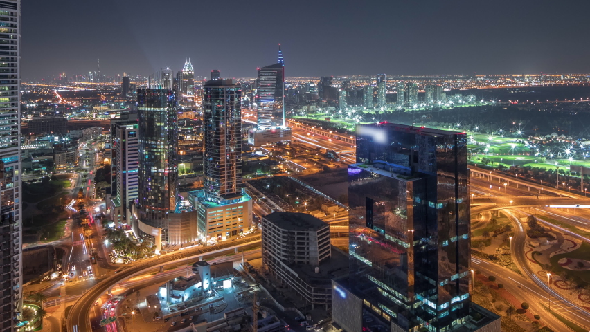 Panorama showing media city, Dubai marina and JLT illuminated skyscrapers along Sheikh Zayed Road with big crossroad junction aerial night timelapse. Rising moon over residential and office buildings