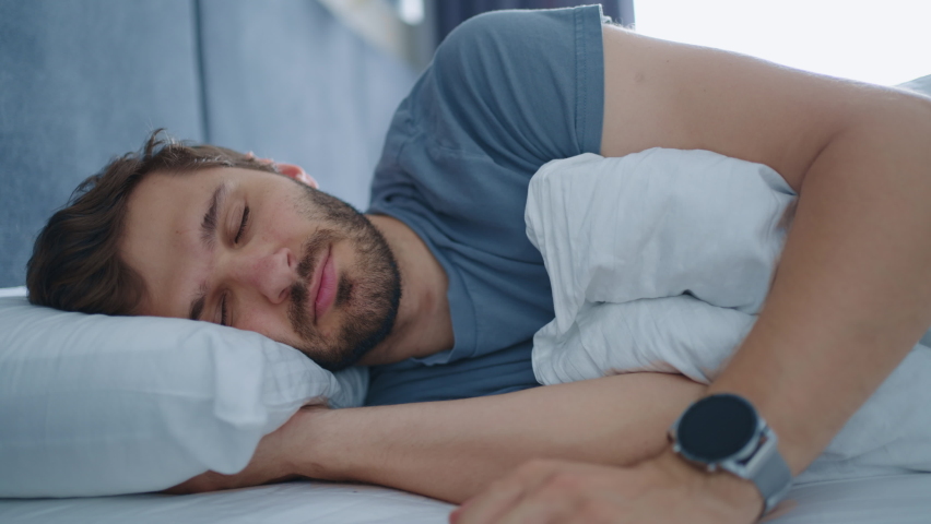 man is sleeping in bedroom in morning, waking up by alarm signal, good mood in early morning time Royalty-Free Stock Footage #1093947171
