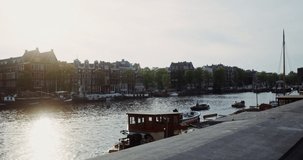 Panoramic view of a beautiful European city with traditional houses along the canal. Many boats are on the water. Netherlands, Amsterdam, on a clear sunny day. Video in 4k, red komodo