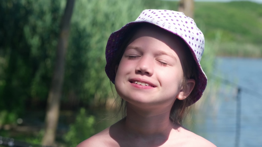 Mother apply protective sunscreen on daughter face at riverbank in summertime holiday vacation. Woman hand with care putting sun lotion on child skin. Kid girl with sunblock in camping taking sunbath
