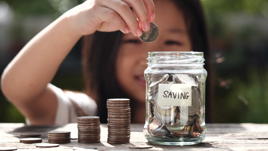 Saving Money. Happy Asian child girl save money by putting coins in glass jar, coin stack growing. Concept save money, cash, education, growth, finance, bank, investment, management, income, business | Shutterstock HD Video #1093952753