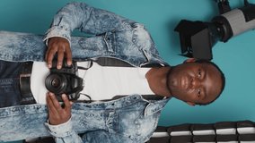 Vertical video: Male photographer using dslr camera and lens to take pictures in studio backstage, capturing photos with professional equipment. Using focused view to photograph images over background - Powered by Shutterstock - Get 15% off with code: PIKWIZARD15