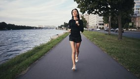 Slow motion video of a girl jogging in a city. The athlete is engaged in training. Fitness outdoors. Sport concept.