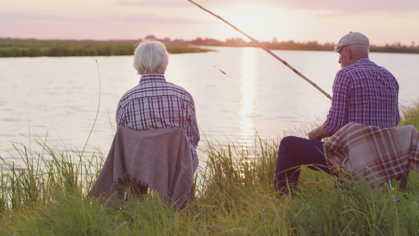 Happy old couple together embracing sitting on lake beach in sunshine outdoors. Candid affectionate feelings, live joyful human emotions, real harmony love, tenderness and care of two retired lovers Royalty-Free Stock Footage #1093958197