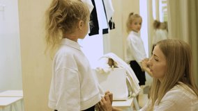 A little girl trying on a jacket and skirt with her mother in the dressing room. Girl looks at herself in the mirror. Slow motion video - Powered by Shutterstock - Get 15% off with code: PIKWIZARD15