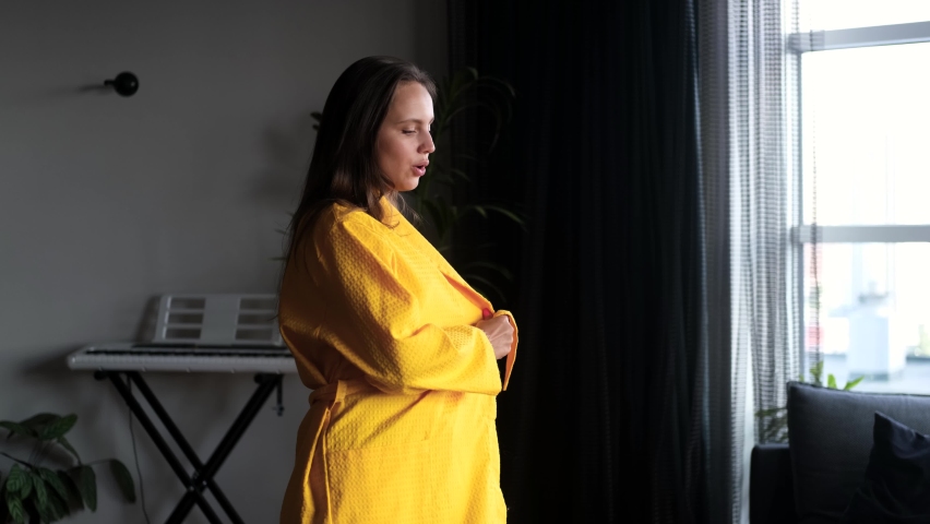 Happy mood concept. Beautiful woman in yellow bathrobe dancing at home