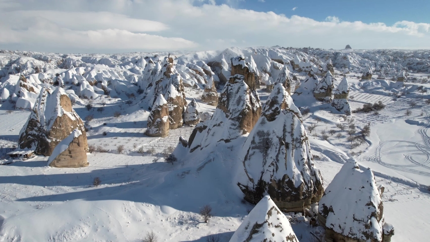 The Cappadocia region in Turkey attracts its visitors with its unique structures. These images were taken with a drone during the winter months. The fairy chimneys turn white with the falling snow in  Royalty-Free Stock Footage #1093973953